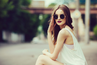 beautiful girl in sunglasses sitting on the asphalt